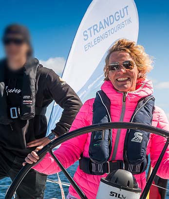 Lächelnde Frau am Steuer eines Segelbootes